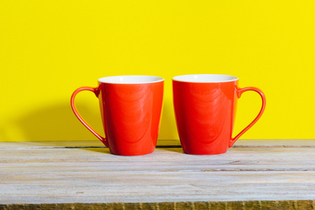 Two mugs of coffee or tea in bold color setting with red on yellow background and shadowの写真素材