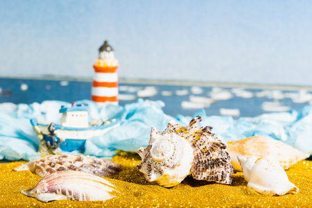 Vacation concept with beach decoration shells,  boat and lighthouse on wave ocean backgroundの写真素材