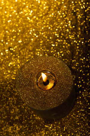 Close-up macro with shallow depth of field of flame in christmas candle with gold glitter backgroundの写真素材