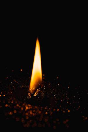 Close-up macro with shallow depth of field of flame in christmas candle with gold glitter backgroundの写真素材
