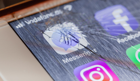 BERLIN, GERMANY - OCTOBER 15, 2018: Facebook Messenger app on a broken screen of an iPhone 7 Plus...