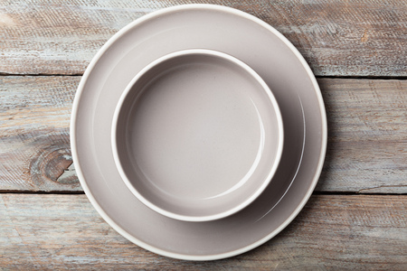 Empty pastel colored plates and salad bowl on grunge wood plank desk with copy spaceの写真素材