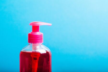 Pump bottle with red soap, container on waood table over blue backgroundの写真素材