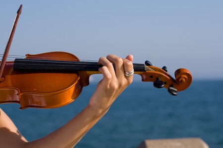 young beautiful blond woman play violin on beachの写真素材