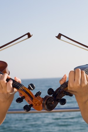 two beautiful young women play violins on beach