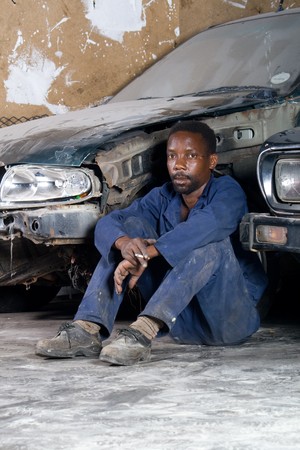 african mechanic resting in garage during lunch breakの写真素材