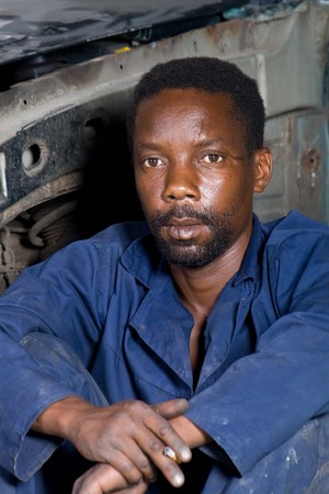 african mechanic resting in garage during lunch breakの写真素材