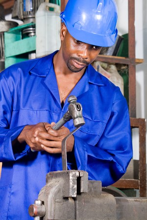 african machinist hammering on metal materialの写真素材