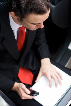 young businessman sitting inside a car and working on laptopの写真素材
