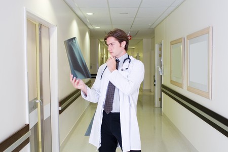 male doctor studying patient's x-ray in the hallway inside hopitalの写真素材