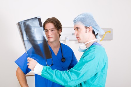 two male doctors looking at x-ray film in ward