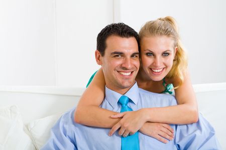 happy young couple hugging on sofaの写真素材
