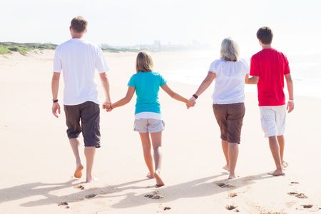 family hand in hand on beachの写真素材