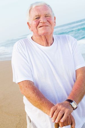 happy senior man on beach with caneの写真素材