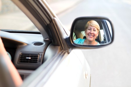 happy senior woman looking in side mirrorの写真素材