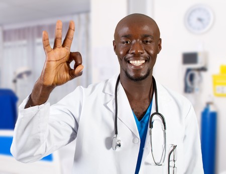 happy african doctor giving OK hand sign in hospitalの写真素材