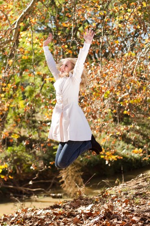 happy young woman jumping in autumn forestの写真素材