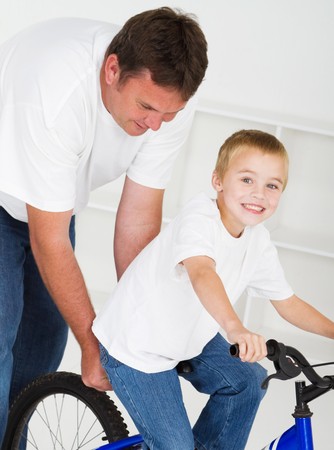 father teaching young son to ride bikeの写真素材