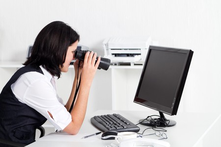 woman looking at computer through binocularsの写真素材