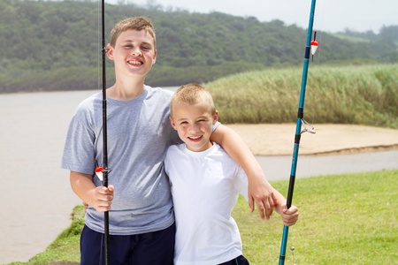 portrait of two little brothers fishing by the lakeの写真素材