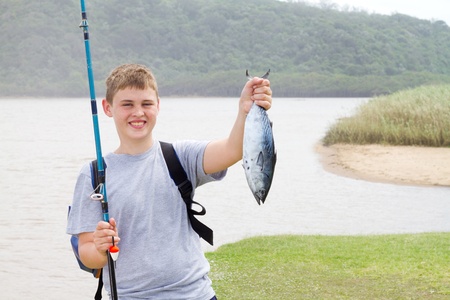 happy teen boy showing a fishing he just caughtの写真素材