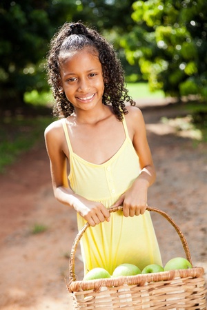 happy little girl with basket of apple in orchardの写真素材