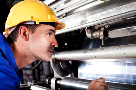 industrial machine operator checking on machine while it