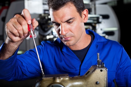 mechanic repairing industrial sewing machineの写真素材