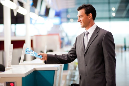 handsome businessman handing over air ticket at airline check in counterの写真素材