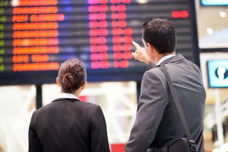 businessman and businesswoman checking flight information at airportの写真素材