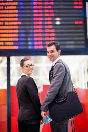 young businesswoman and businessman in front of airport information boardの写真素材