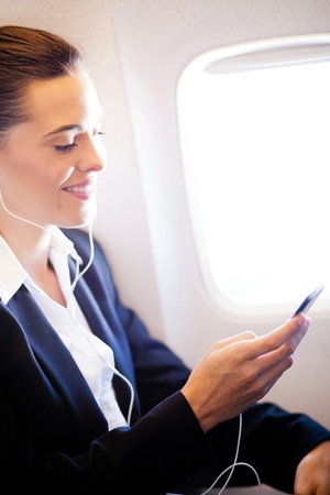 pretty businesswoman listening music on airplaneの写真素材