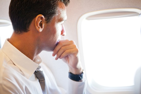 thoughtful businessman on airplane looking outsideの写真素材