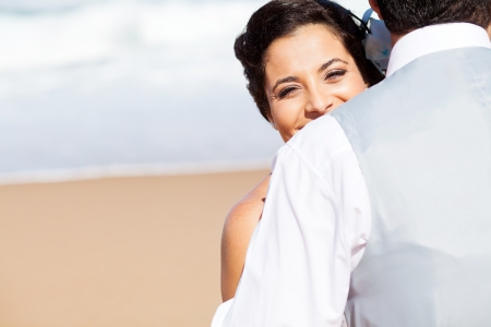 happy young woman hugging husband on beachの写真素材