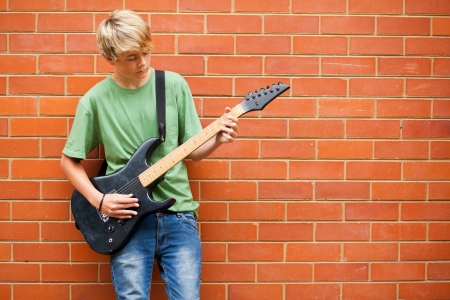 teen boy playing guitar outdoorsの写真素材
