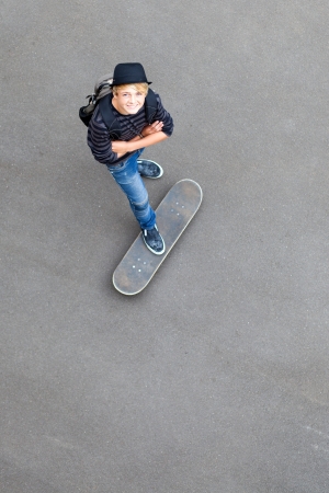 happy teen skateboarder standing on skateboard and looking upの写真素材