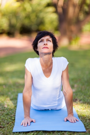 middle aged woman doing yoga stretching outdoorsの写真素材