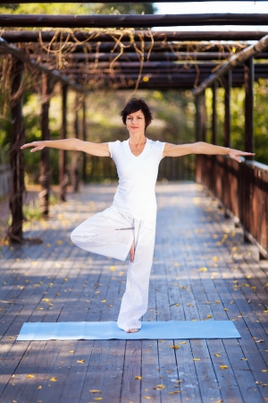 middle aged woman doing yoga pose in gardenの写真素材