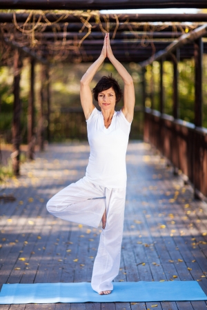 beautiful mature woman yoga pose in gardenの写真素材