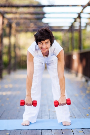 happy middle aged woman working out with dumbbellsの写真素材