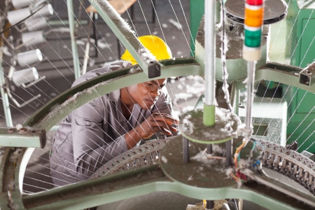african american textile factory technician repairing weving loom