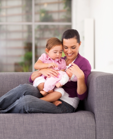 happy mother playing toy with daughter on sofa at homeの写真素材