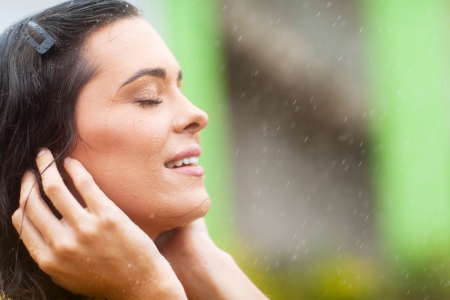 happy young woman enjoying rain falling on her faceの写真素材
