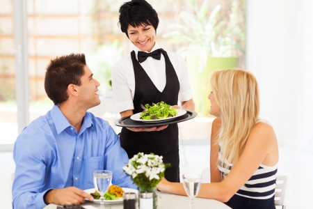 happy waitress serving customers in restaurantの写真素材