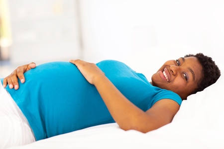 pregnant african american woman lying on bedの写真素材