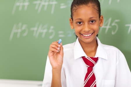 primary schoolgirl holding chalk in front of chalkboardの写真素材