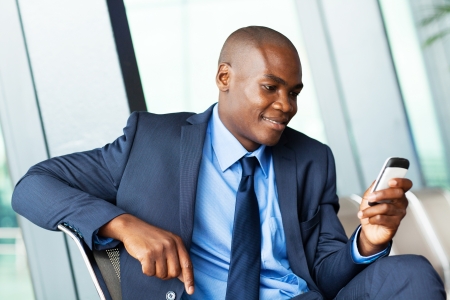 handsome african american businessman using smart phone emailingの写真素材