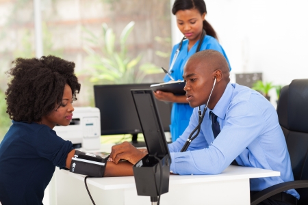 african medical doctor monitoring patient's blond pressure in his office