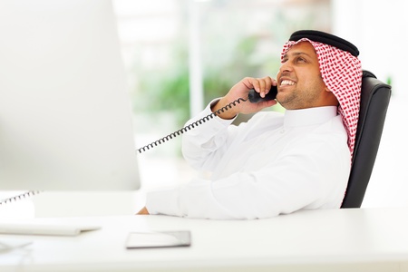 cheerful arabian corporate worker talking on the landline phone