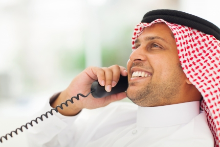 smiling male arabian office worker chatting on the phoneの写真素材